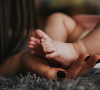 Pessoa segurando os pés do bebê na fotografia de foco seletivo